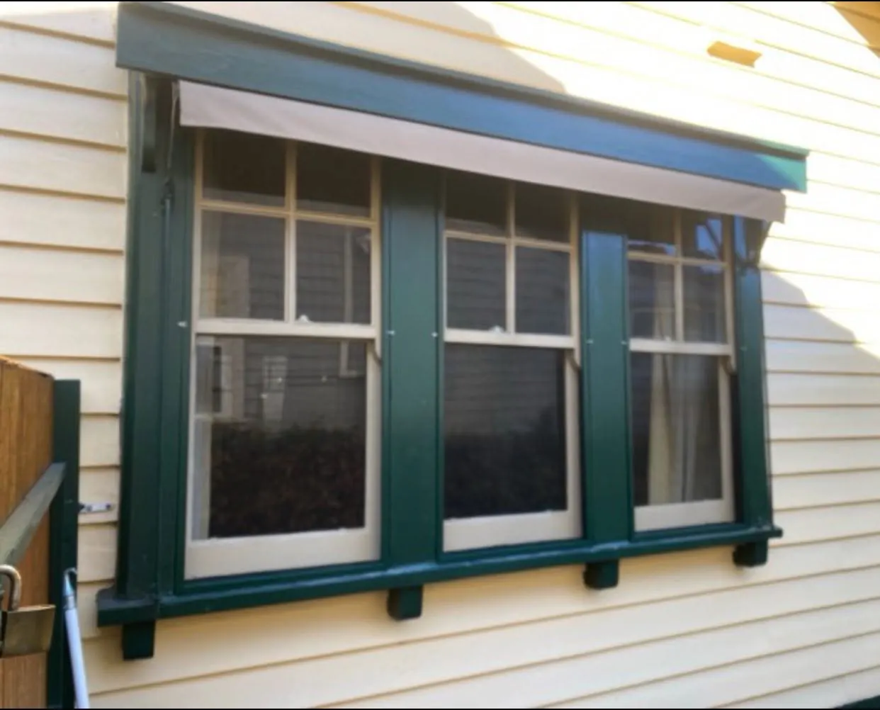Restored double-hung timber windows with heritage green trims