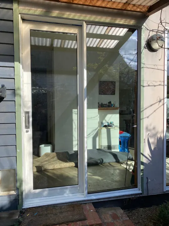 Sliding door and window installed on a blue weatherboard wall