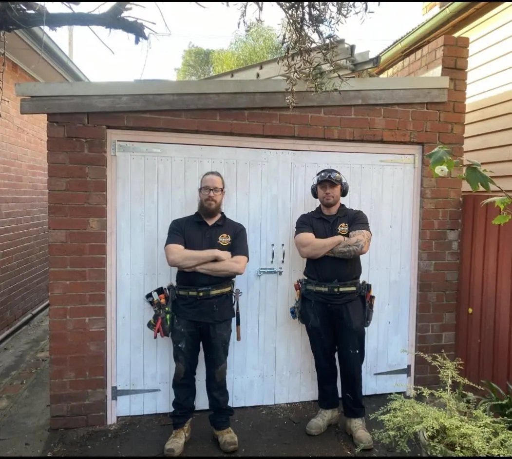 Justin and a NewLife tradesman standing in front of custom white garage doors they built